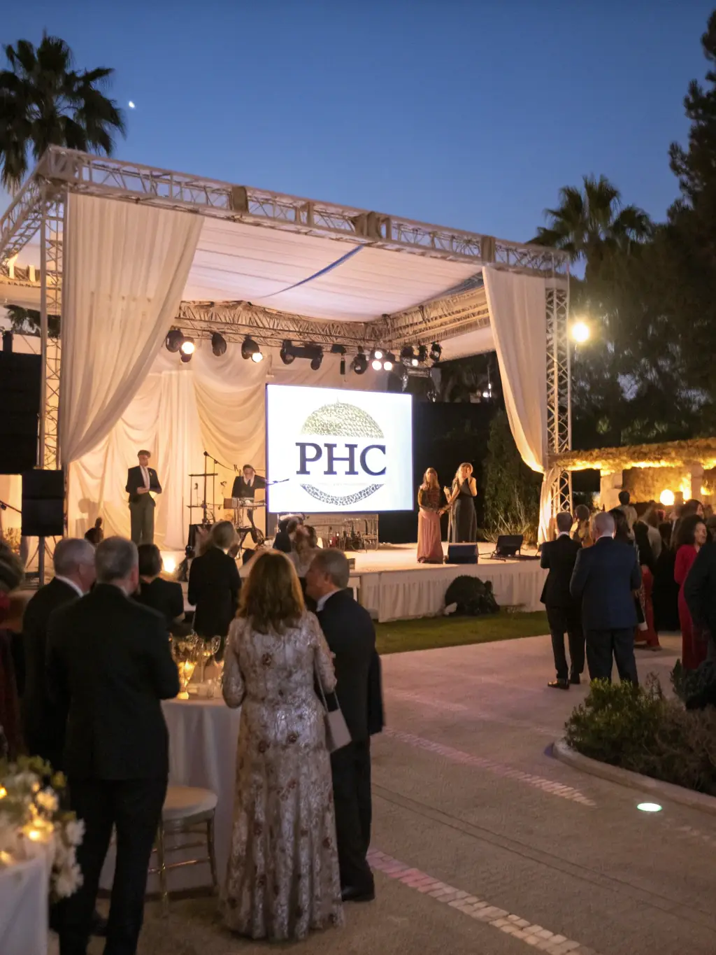 A dynamic photo of a fundraising gala with guests enjoying entertainment, auction tables, and a speaker addressing the audience about the impact of donations.
